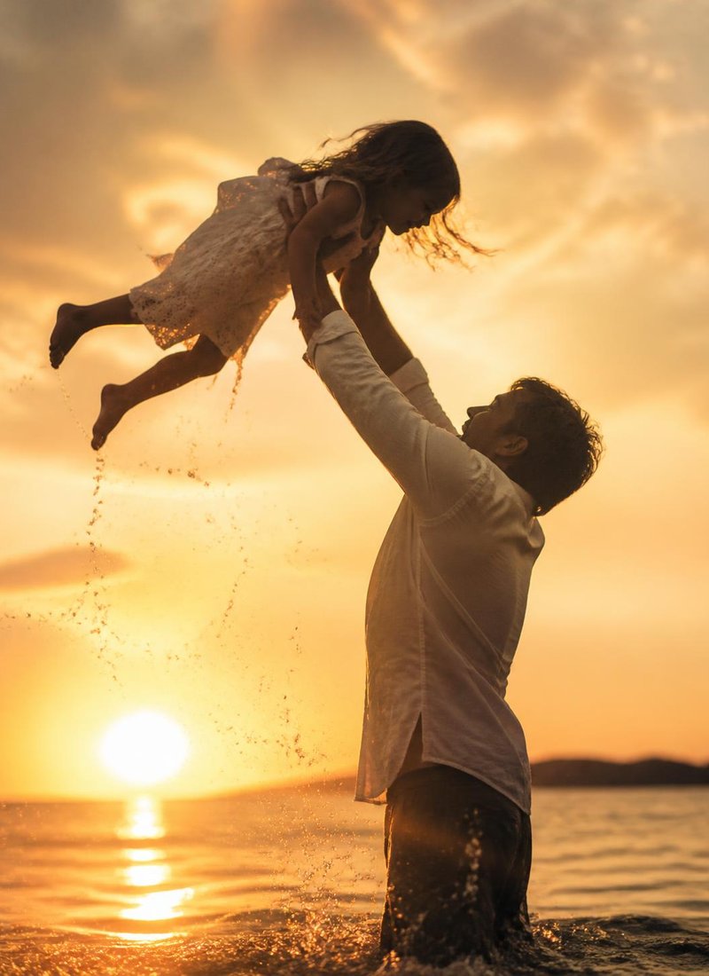 Dad lifting daughter at the water’s edge